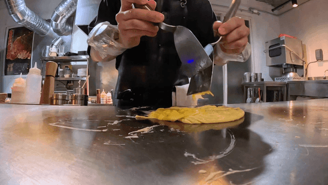 Skilled chef preparing omelet with weights on arm