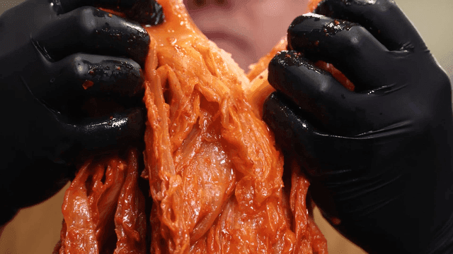 Thick aged kimchi torn apart with gloved hands