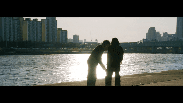 도시 스카이라인을 배경으로 강가에서 무술을 연습하는 두 사람