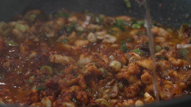 Stir-fried eel sizzling in a frying pan