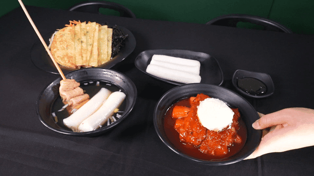 Table filled with tteokbokki, fish cakes, and various snacks