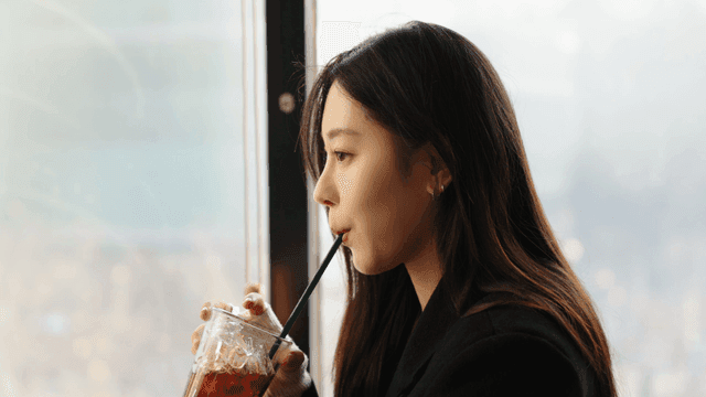 Profile of a woman drinking iced Americano by the window