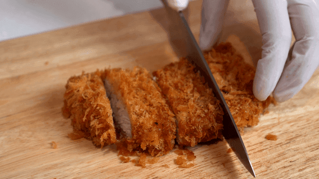 도마 위에서 바삭한 튀긴 돈까스 자르기