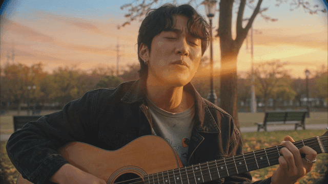 Man singing and playing guitar in park at sunset