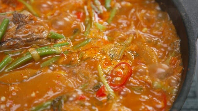 Spicy stew with fresh vegetables and fish is boiling