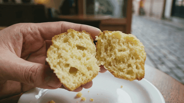 Hands splitting muffin in cozy cafe