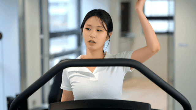 Woman stretching on a treadmill at gym