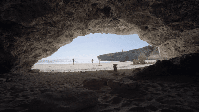 People enjoying a beach view from a cave
