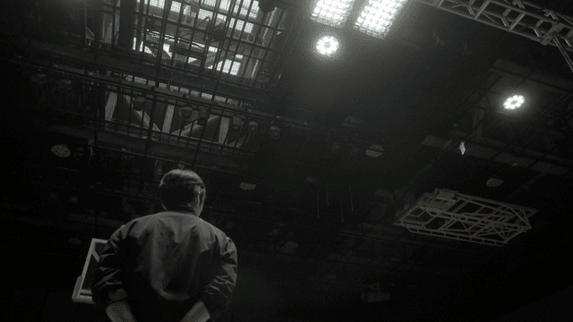 Back view of man looking up at ceiling lights of indoor basketball court