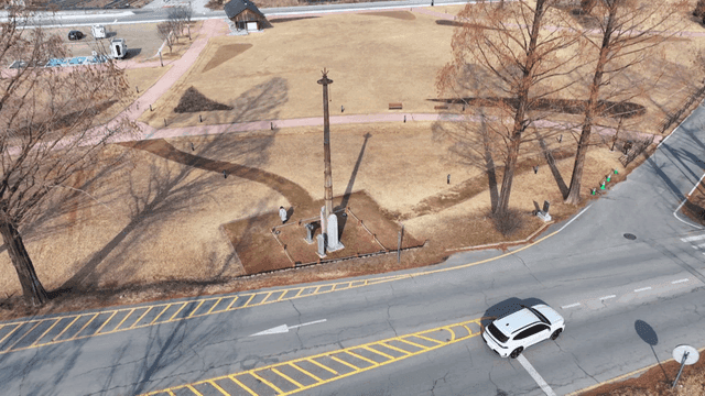 Stone pillars in park with roads and cars