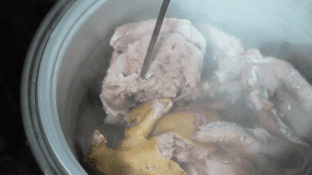 Boiling meat in a pot with steam rising