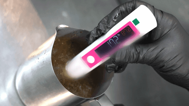 Hand measuring salinity of boiling broth