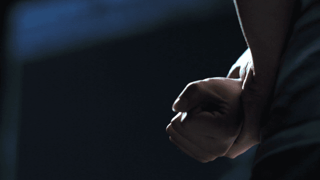 Person's hand with backpack on dark background