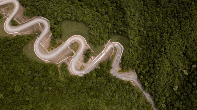 울창한 산 속 구불구불한 도로에서 풍력 터빈 자재를 운반하는 모습
