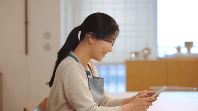 Woman sitting at table using smartphone