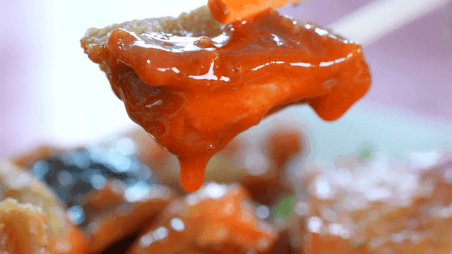 Fried chicken dipped in spicy tteokbokki sauce