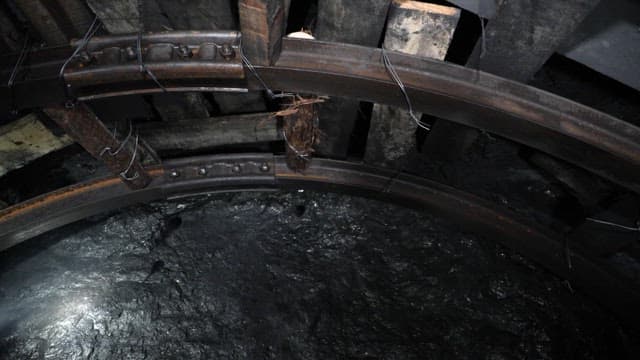 Wood and metal structure of dark coal mine tunnel ceiling