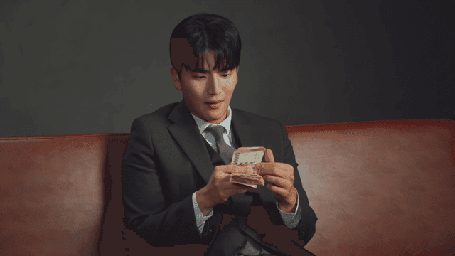 Man in a suit counting money on a sofa