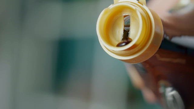 Brown Oil Being Poured from the Spout of the Bottle