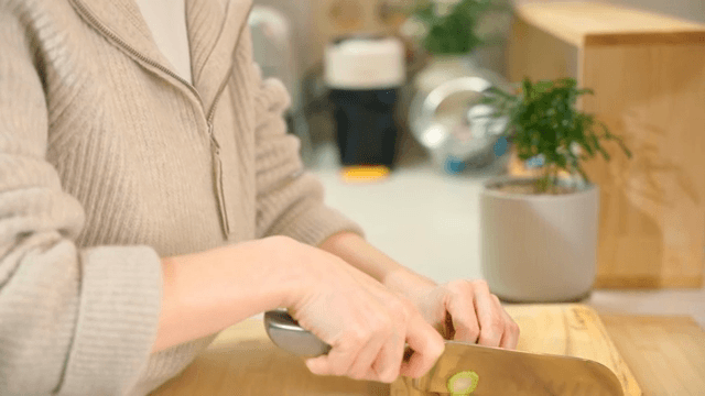 Woman slicing cucumber in a cozy kitchen