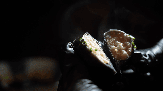 Gloved hand holding steaming dim sum