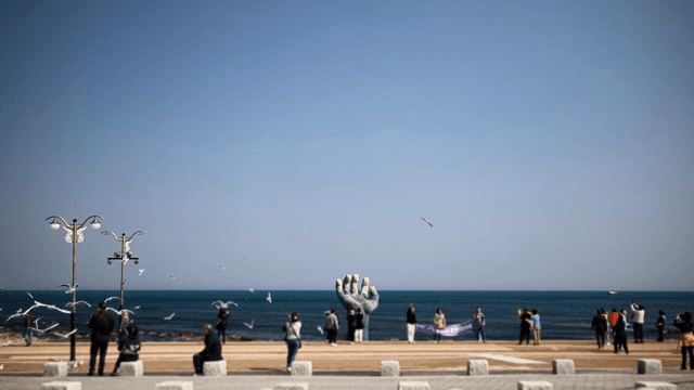 조각상이 있는 바닷가 풍경을 즐기는 사람들