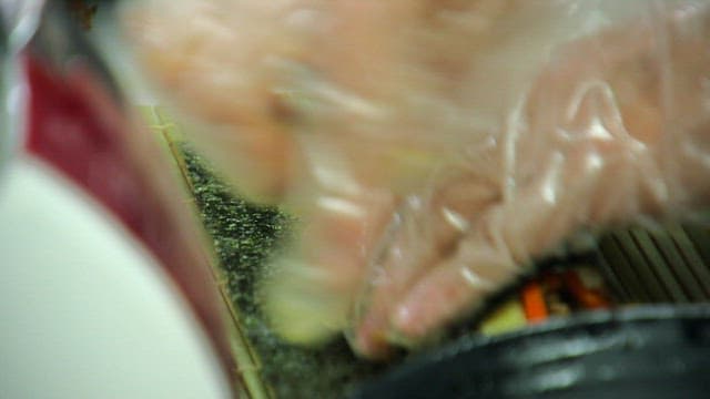 Hands rolling kimbap with precision