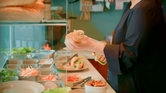 Woman preparing sandwich with fresh ingredients