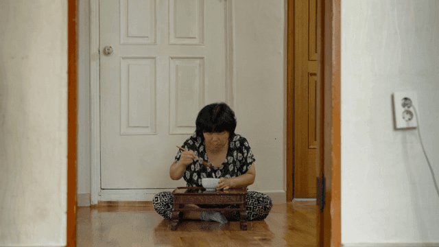 실내에서 혼자 식사하는 노인 여성