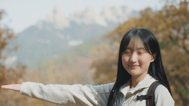 Young woman smiling at autumn scenery on high mountain