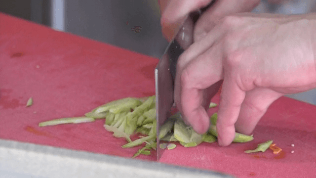 빨간 도마 위에서 오이를 써는 모습