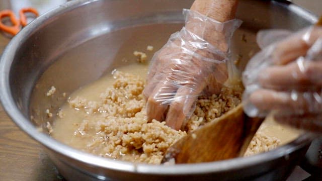 Mixing brown rice and water in a stainless steel bowl to make leaven