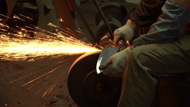 Worker sharpening a knife with sparks