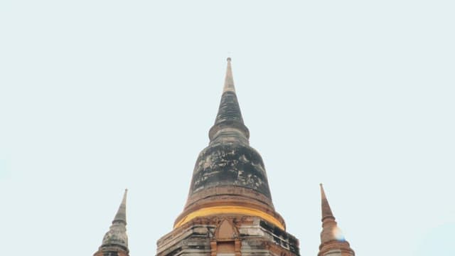 Tourists climbing steps towards ancient Thai temple with spires