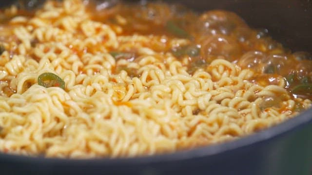냄비 속에서 집게로 저으며 끓이고 있는 맛있는 라면