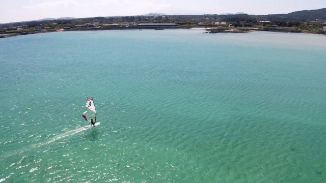 맑은 청록석 바다 위를 미끄러지는 윈드서퍼