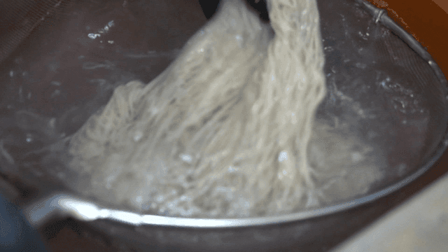 찬물에 메밀면을 빠르게 헹구는 장면