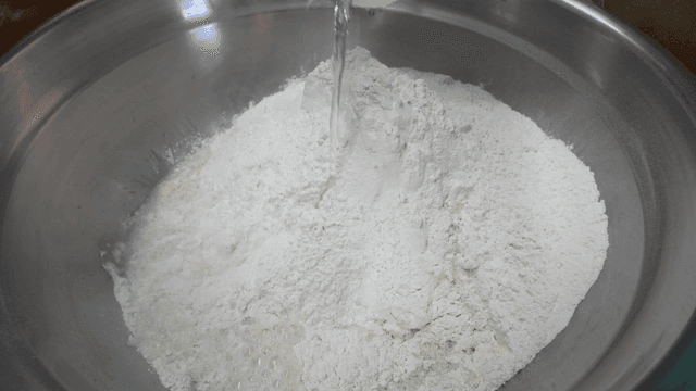 Measuring cup for pouring water into flour in bowl