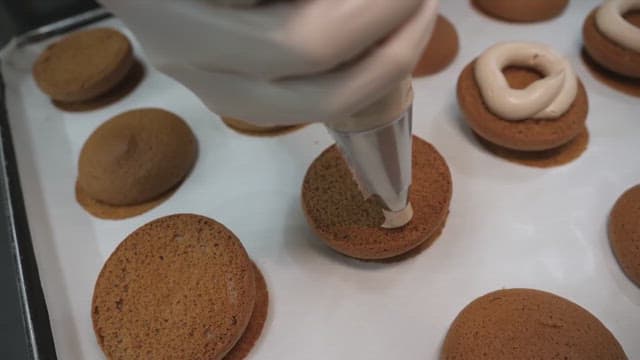 Piping cream onto freshly baked cookies in a bakery