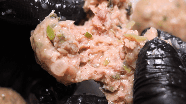 Juicy rolled dumplings torn apart by gloved hands.