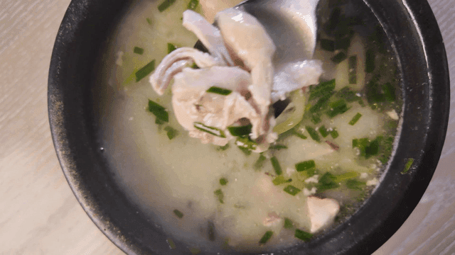 Spoon scooping out chicken soup boiled with green onions