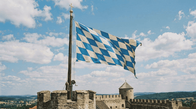 Flag of Bavaria, Germany, fluttering atop historic castle tower