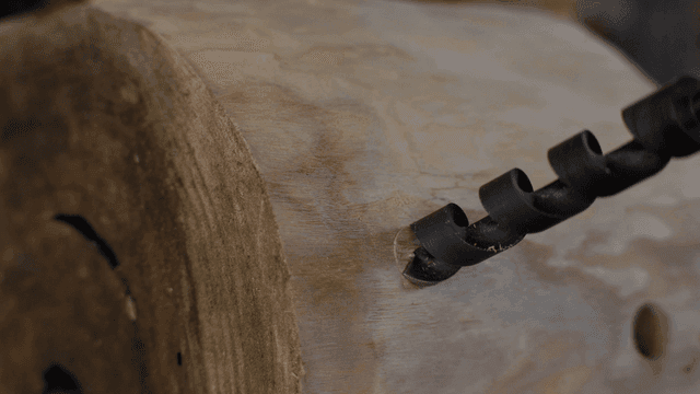 나무 통에 천천히 구멍을 뚫는 나선형 드릴