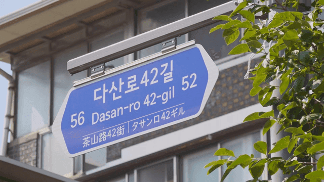 건물과 나뭇잎이 있는 도로 표지판