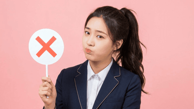 Female student holding sign with X mark