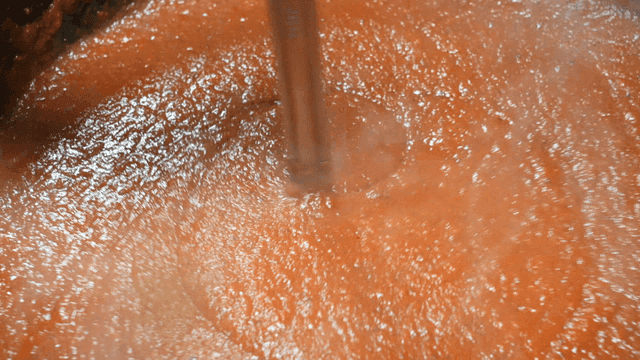 Thick tomato sauce being stirred in a pot