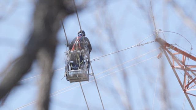 Electrician moving to inspect the high-voltage lines on a transmission tower