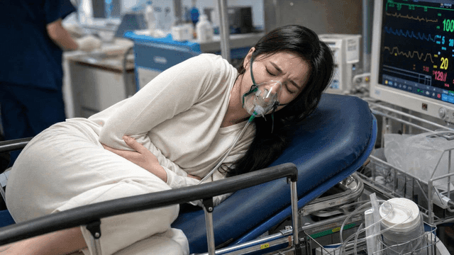 Female patient wearing oxygen mask complaining of abdominal pain in emergency room