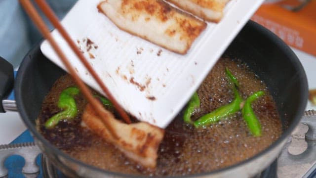 Cooking hairtail and chili peppers in soy sauce boiling in a pan