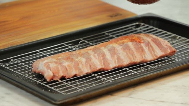 Applying sauce to pork ribs on a baking tray